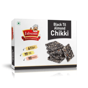 Box of Jabsons Black Til Almond Chikki with image of brittle pieces on white packaging, brand logo and product name visible - Jabsons Almond Chikki Black Til 270gm